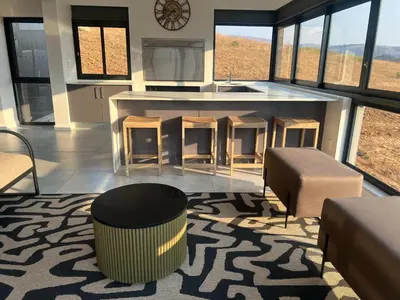 a living room with a kitchen and a counter with stools at Hururu House in Dullstroom