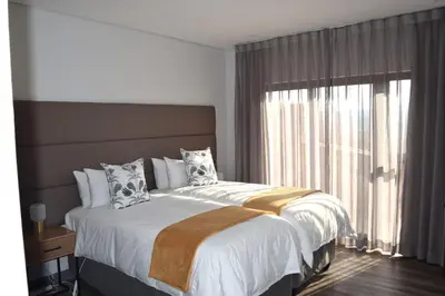 a bedroom with a large bed with a large window at Hururu House in Dullstroom