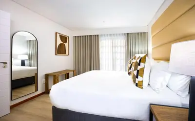 a hotel room with a large bed and a mirror at ILanga Air B&B in Nelspruit