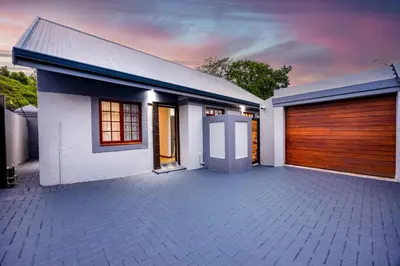 a white house with a wooden garage door at ILanga Air B&B in Nelspruit