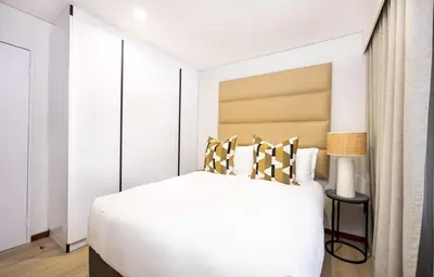 a bedroom with a white bed with gold and black pillows at ILanga Air B&B in Nelspruit
