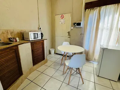 a small kitchen with a table and a microwave at Tranquilo Guesthouse in Ermelo