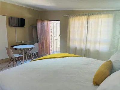 a bedroom with a bed and a table with chairs at Tranquilo Guesthouse in Ermelo