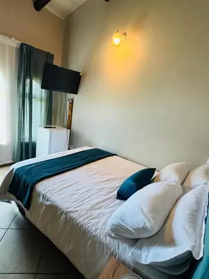 a bedroom with a bed with white sheets and blue pillows at Tranquilo Guesthouse in Ermelo