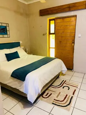 a bedroom with a bed and a door and a rug at Tranquilo Guesthouse in Ermelo