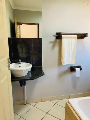 a bathroom with a white sink and a mirror at Tranquilo Guesthouse in Ermelo