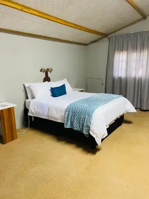 a bedroom with a bed with a blue pillow on it at Tranquilo Guesthouse in Ermelo
