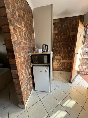 a kitchen with a stove and a brick wall at Tranquilo Guesthouse in Ermelo