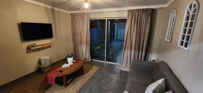 a living room with a couch and a television at Lazél Apartments in Ermelo