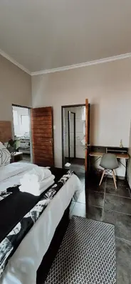 a bedroom with a bed and a desk in it at Lazél Apartments in Ermelo