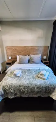 a bedroom with a large bed with two towels on it at Lazél Apartments in Ermelo