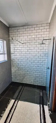 a bathroom with a shower with white tiled walls at Lazél Apartments in Ermelo