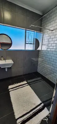 a bathroom with a sink and a white rug at Lazél Apartments in Ermelo