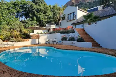 a swimming pool in front of a house at Waters View Villa, 5 Bedroom House in Hartbeespoort