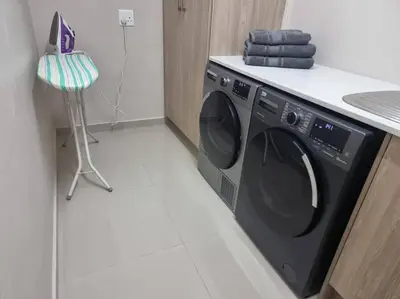 a black washing machine in a kitchen with a counter at Waters View Villa, 5 Bedroom House in Hartbeespoort