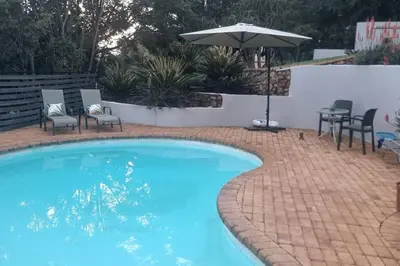 a swimming pool with chairs and an umbrella at Waters View Villa, 5 Bedroom House in Hartbeespoort
