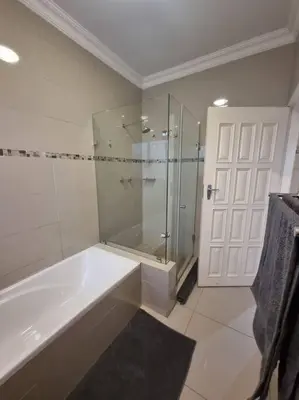 a bathroom with a tub and a glass shower at Waters View Villa, 5 Bedroom House in Hartbeespoort