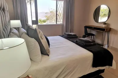 a bedroom with a bed with pillows and a mirror at Waters View Villa, 5 Bedroom House in Hartbeespoort