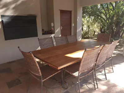 a dining room table with chairs and a flat screen tv at Zebula Golf and Wildlife Estate - Africa Breathing Pax 8 - Moi Signature Exclusive Villa in Mabula