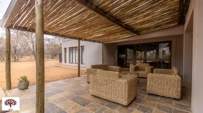 a patio with wicker chairs under a wooden pergola at Zebula Golf and Wildlife Estate - Africa Breathing Pax 8 - Moi Signature Exclusive Villa in Mabula