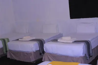three beds in a room with white sheets at Vutomi Guesthouse in Burgersfort