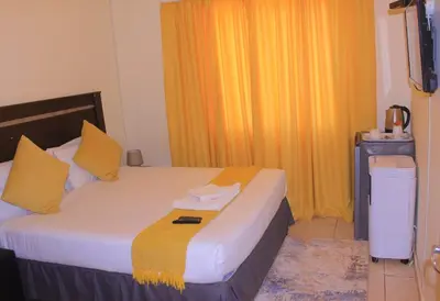 a hotel room with a bed with yellow curtains at Vutomi Guesthouse in Burgersfort