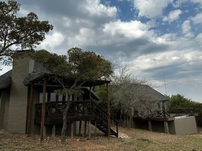a house with a wooden deck next to a tree at Mokaikai - Leopards Leap - Moi Exclusive Luxury Villa in Mabula