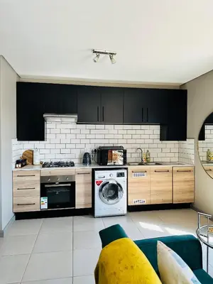 a kitchen with black cabinets and a washer and dryer at Centurion Marnard Luxury Apt in Centurion