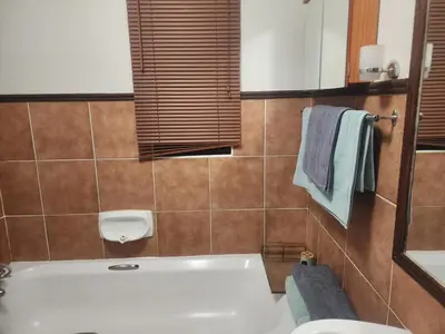 a bathroom with a tub and a sink and towels at Beagle Sands in Pretoria