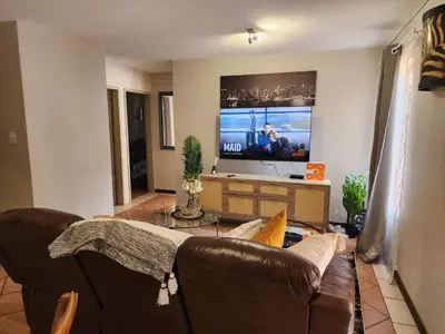a living room with a brown couch and a tv at Beagle Sands in Pretoria