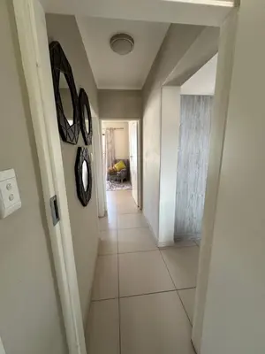 a hallway with a white tile floor and a clock on the wall at Tranquility in Carlswald in Midrand