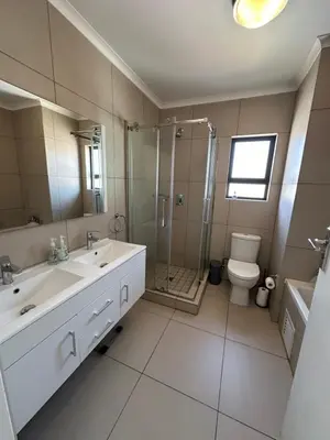a bathroom with a sink and a shower and a toilet at Tranquility in Carlswald in Midrand
