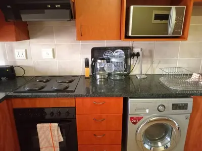 a kitchen with a stove and a washing machine at Calswald's Skyline Sanctuary in Midrand