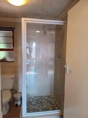 a bathroom with a glass shower with a toilet at Calswald's Skyline Sanctuary in Midrand