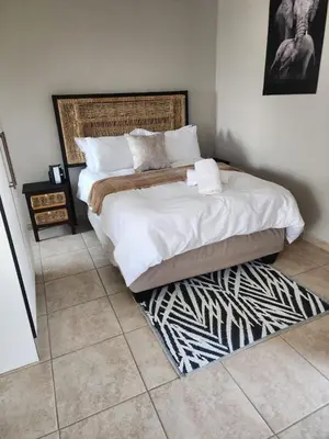 a bedroom with a large bed and a rug at khutsong Apartments in Secunda