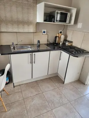 a kitchen with white cabinets and a sink and a microwave at khutsong Apartments in Secunda