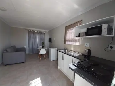a kitchen and living room with a couch and a microwave at khutsong Apartments in Secunda