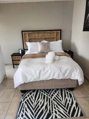 a bedroom with a large bed with white sheets and pillows at khutsong Apartments in Secunda