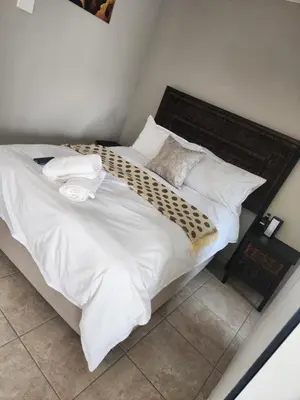 a large bed with white sheets and pillows at khutsong Apartments in Secunda