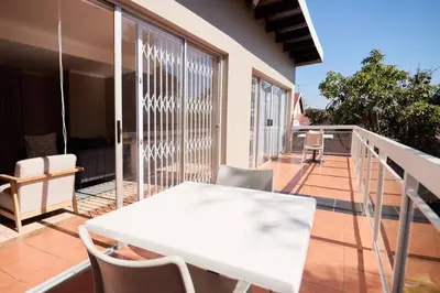 a white table and chairs on a balcony at Cozy Apartment close to Menlyn in Pretoria