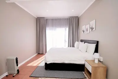a bedroom with a white bed and a window at Cozy Apartment close to Menlyn in Pretoria
