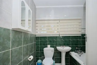 a green tiled bathroom with a toilet and a sink at Cozy Apartment close to Menlyn in Pretoria