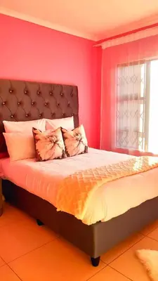 a bedroom with a large bed with pink walls at Palma spaces in Pretoria