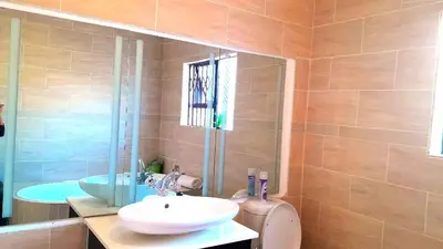 a bathroom with a sink and a toilet and a mirror at Palma spaces in Pretoria