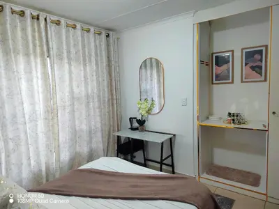 a bedroom with a bed and a table with a mirror at Palma spaces in Pretoria