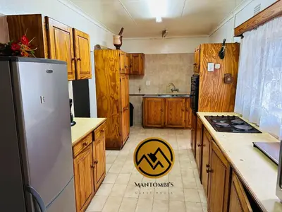 a kitchen with wooden cabinets and a stainless steel refrigerator at Mantombi's Guest House in Graskop