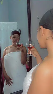 a woman holding two wine glasses in front of a mirror at Mantombi's Guest House in Graskop