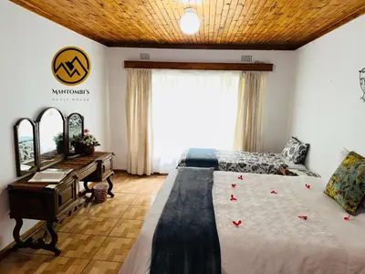 a bedroom with a bed and a desk and a window at Mantombi's Guest House in Graskop