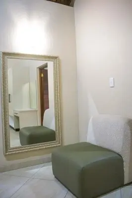 a mirror and a green ottoman in a room at Keleo Safari Lodge in Bela-Bela