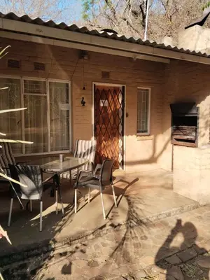 a patio with a table and chairs in front of a house at Luilekker Chalets in Waterval-Onder